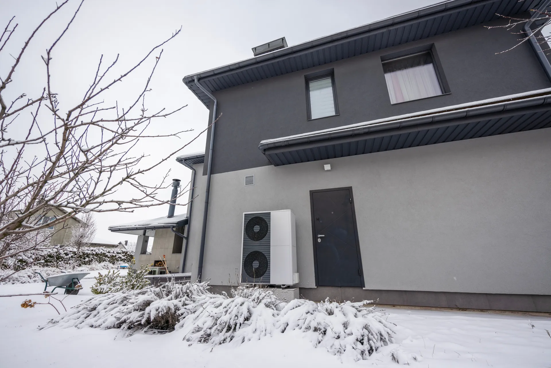 Wärmepumpe im Winterbetrieb vor einem Wohnhaus